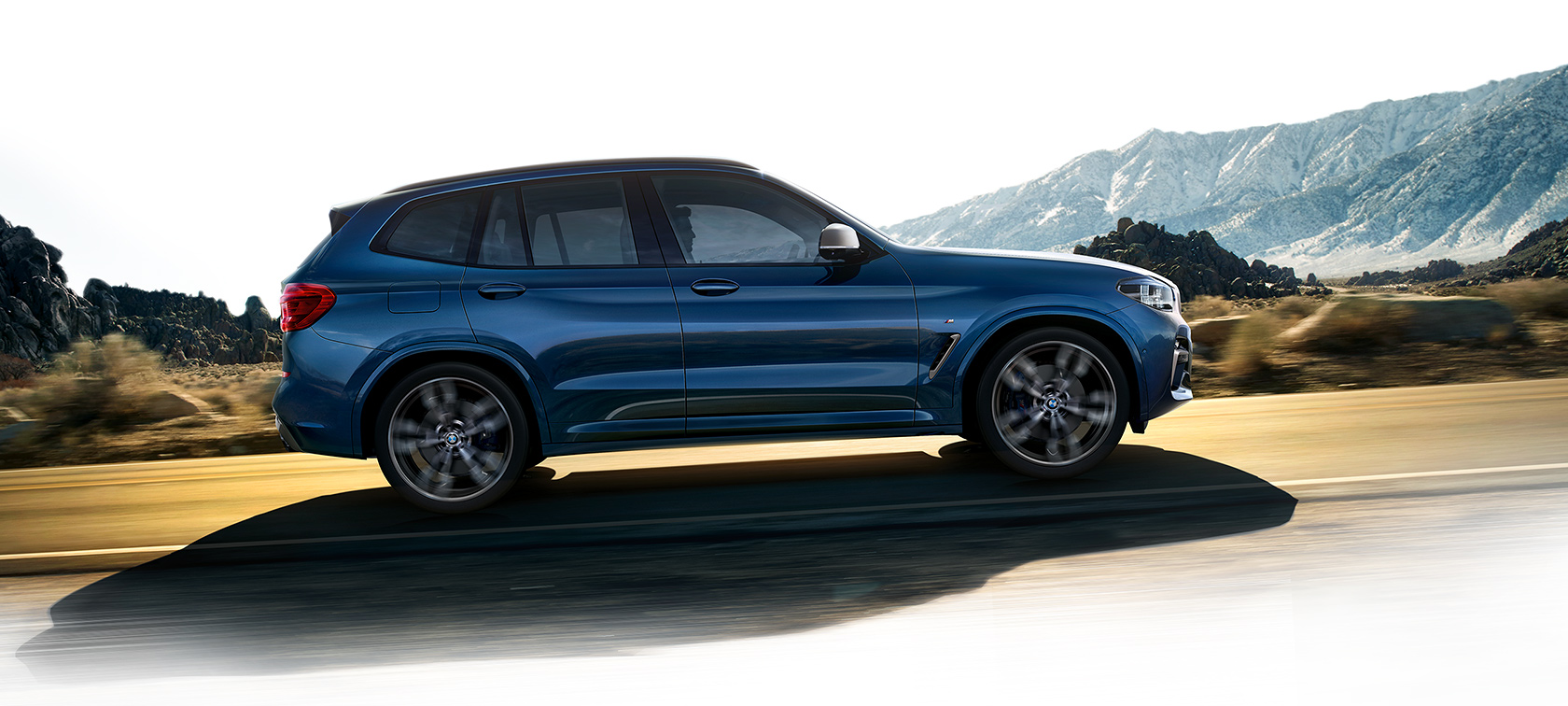 BMW X3 azul subindo estrada de asfalto em velocidade BMW X3 azul subindo estrada de asfalto em velocidade